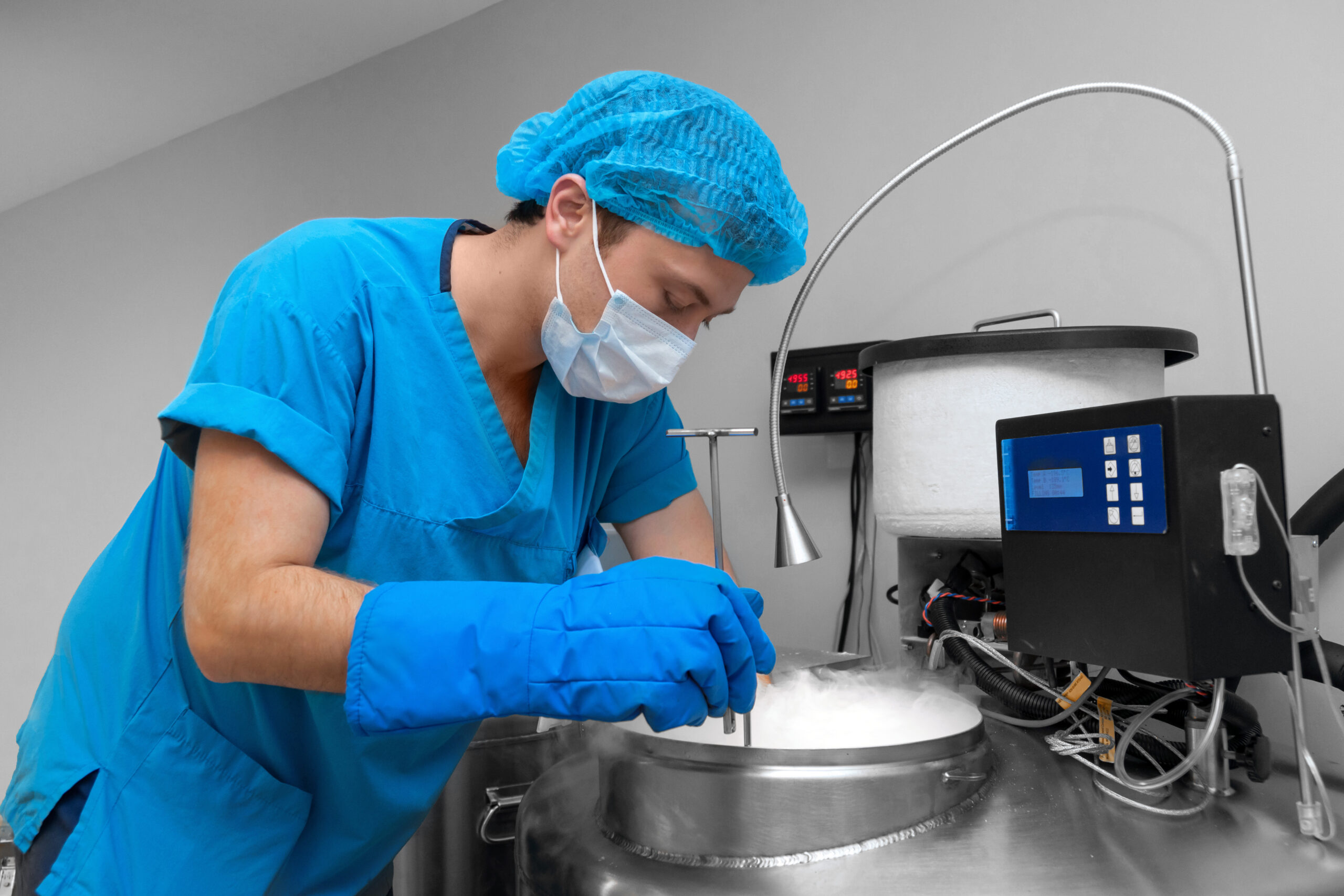 Embryologist lowering frozen egg samples into a liquid nitrogen storage tank